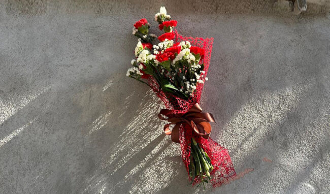 Un bouquet di garofani rossi sotto la lapide dedicata a Elio Vittorini